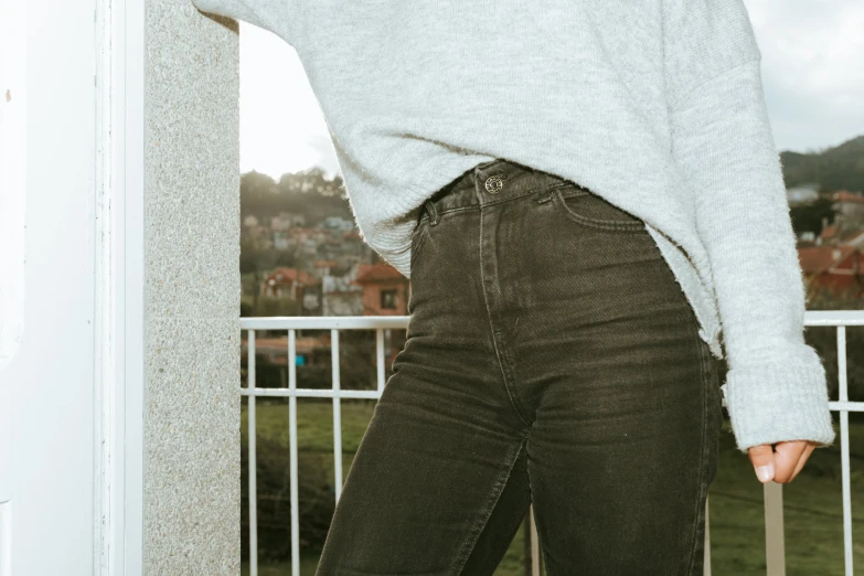 a woman standing on a balcony wearing a sweater