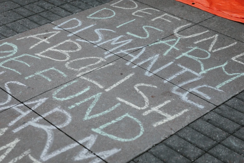 chalk writing on asphalt near orange umbrella and sidewalk