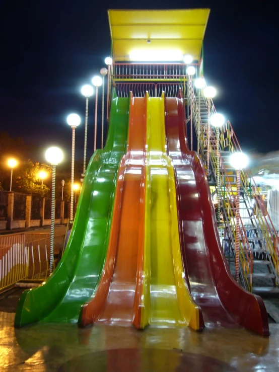 a brightly colored slide at night by some lights