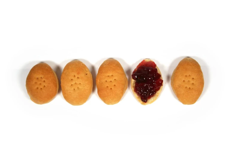 five biscuits with jam spread over them to make an odd shape