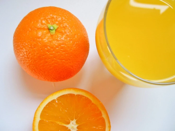 a glass of orange juice with an orange and the other two slices