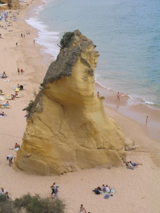 people on the beach near an overhanging rock