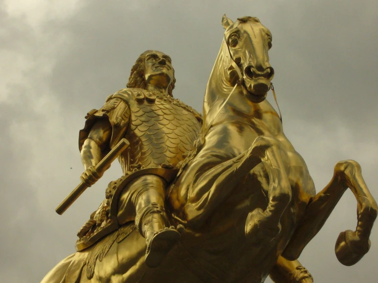 a golden statue of a man on horseback holding a flag