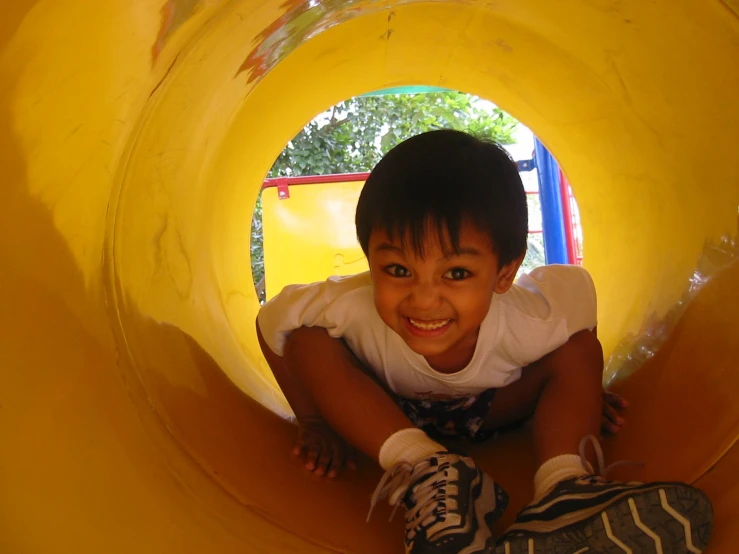 small child smiling in yellow tube, while sitting down