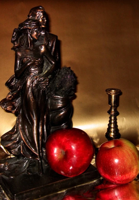 a statue with an apple near an old fashioned light bulb