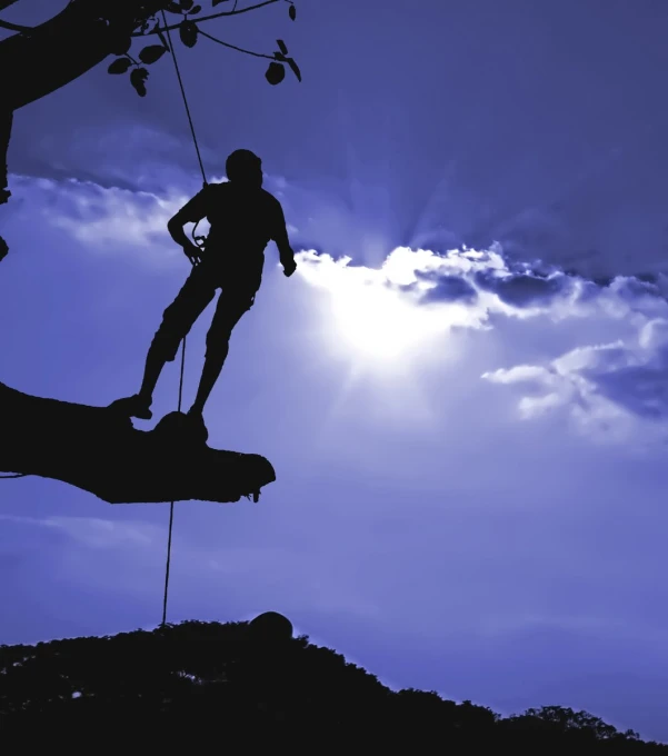 the silhouette of a man climbing up a mountain