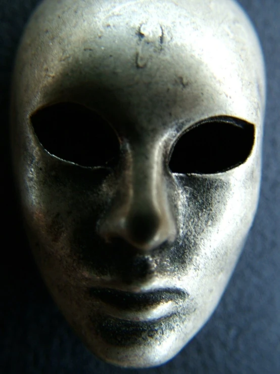 a close up of a silver mask with no eyes