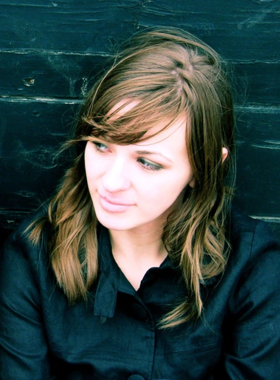 a woman leaning against a wooden wall with her eyes closed