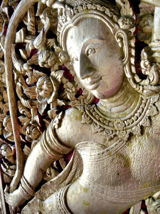 a wooden carving of a lady holding a leaf