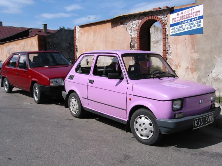 two purple cars parked next to each other in front of an old building