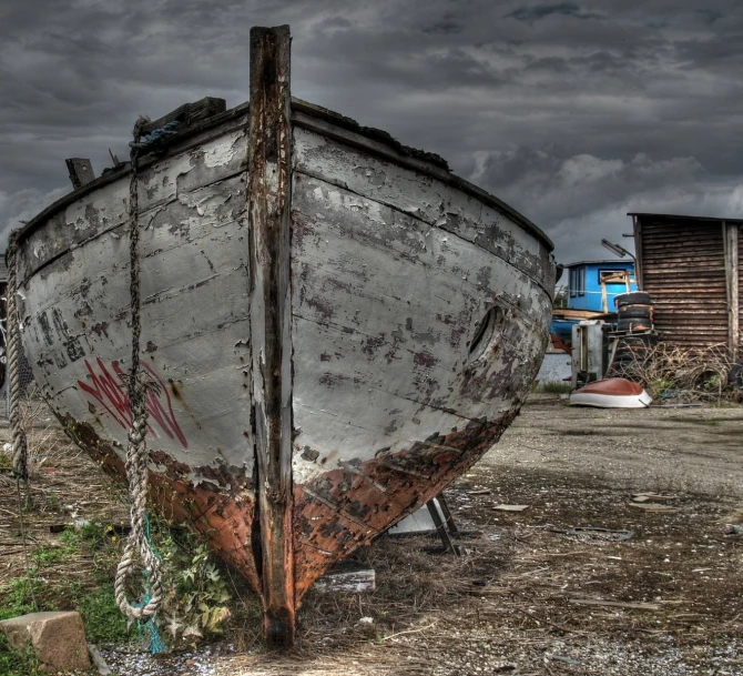 a rusted boat with white paint sitting on the shore