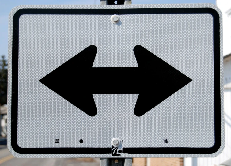 an arrow sign in the street next to a white building