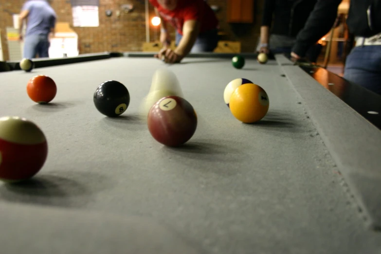 several pool balls in an orderly line and one ball being tossed at