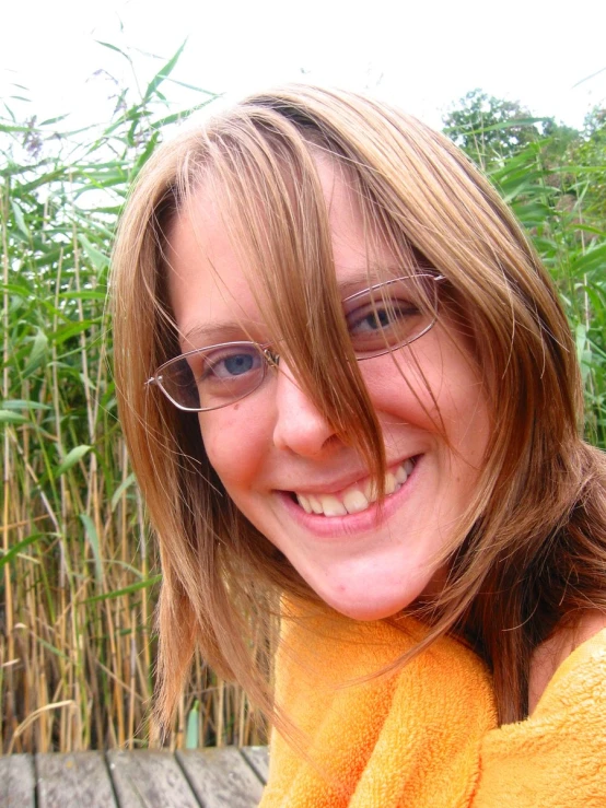 a blonde girl with glasses in front of some plants