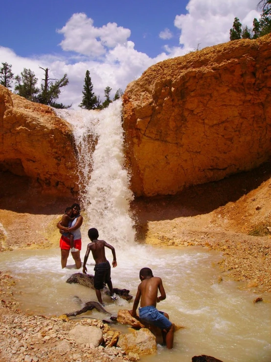 s are wading in a river next to a waterfall