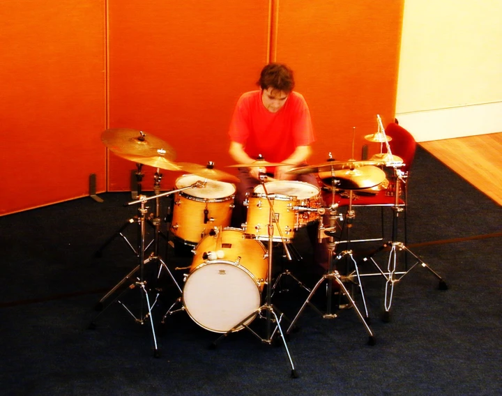 a man plays drums in front of a wall