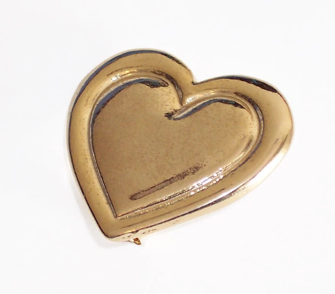 an antique heart shaped gold plated object with thin edges
