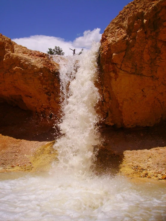 a person stands above a waterfall in a river