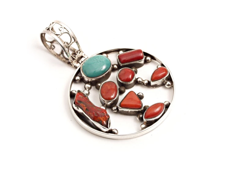 an oval pendant with coral and turquoise stones in it