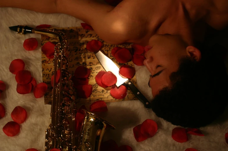 a man laying on top of a floor covered in rose petals next to a saxophone