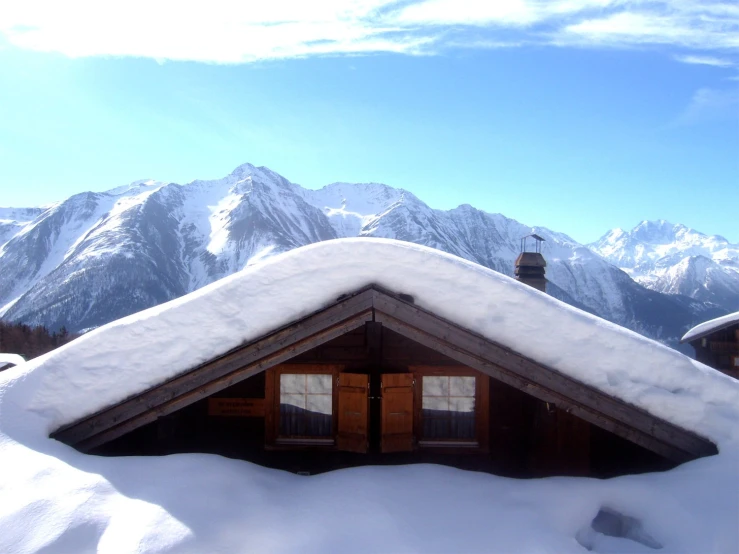 a cabin in the snow surrounded by mountains