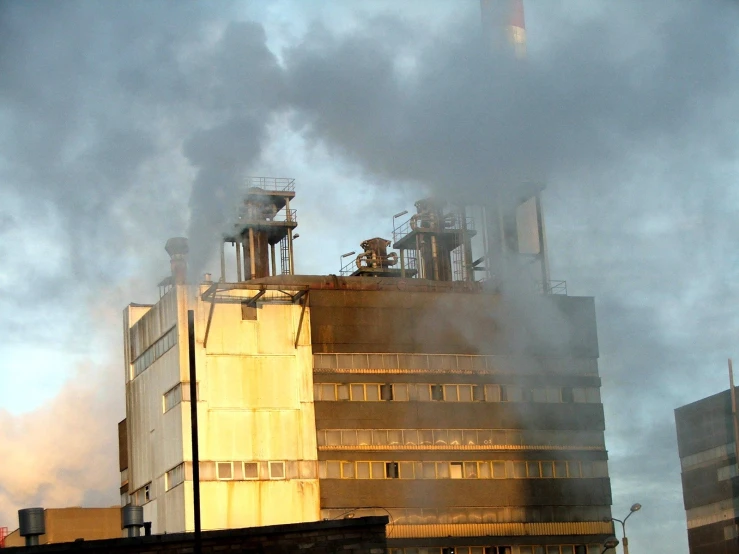 smoke billows from the back of a large industrial building