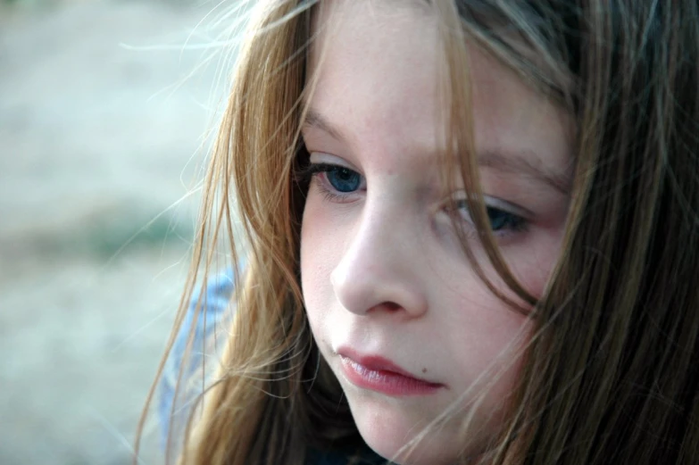 a young child with very long hair looks intently