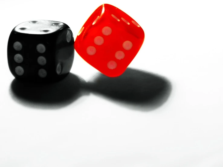 two red and one black dice sitting on top of a white counter