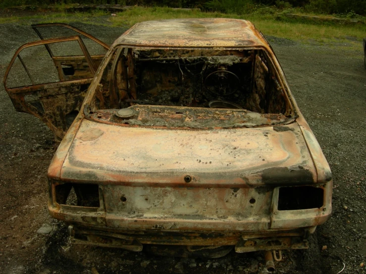an old car with rusty paint sitting on dirt