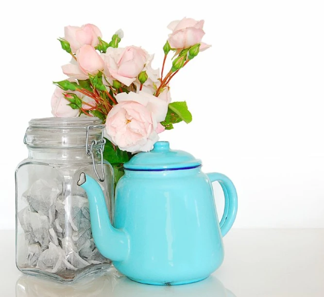a blue pot with flowers in it next to a cup full of silver coins
