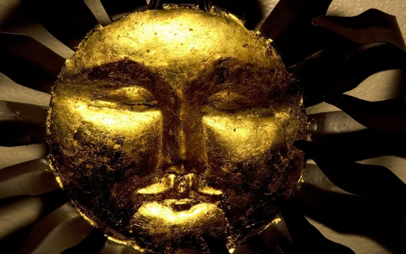 a golden metal face with big, decorative eyes