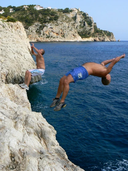 two men diving off a cliff into the ocean