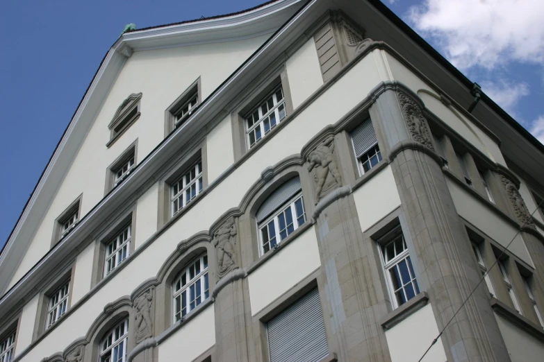 a building with four windows and a green sign on the corner