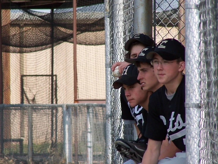 a group of boys sitting next to each other in front of a baseball field