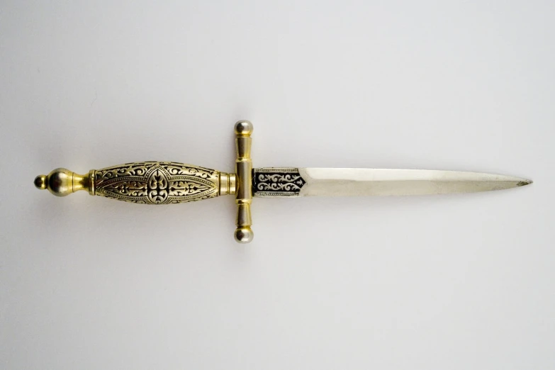 a gold - plated knife sitting on a white surface