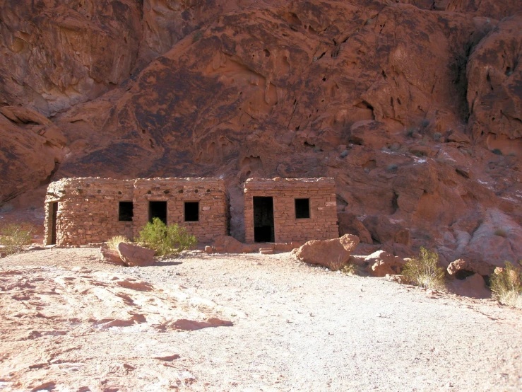 two small brick buildings sit in front of some red mountains