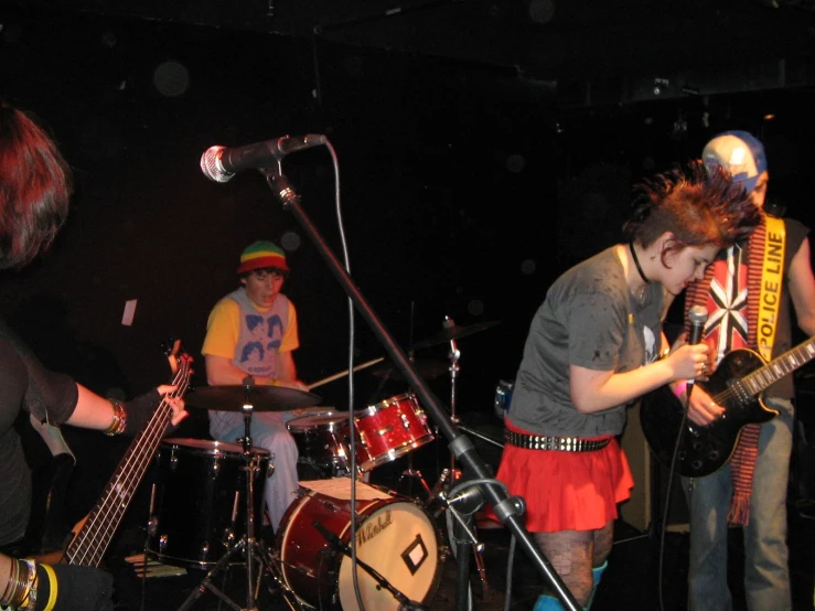 two musicians and one band mate on stage with guitar and drums