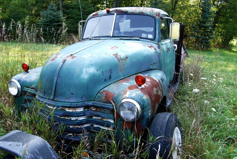 an old blue truck parked in the grass