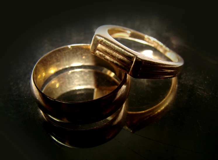 two gold wedding rings are sitting on the surface