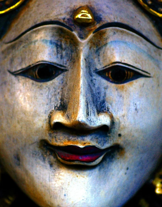 a large buddha statue wearing a mask with red lips