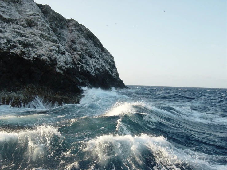 a rock sitting on top of a rocky cliff over looking water