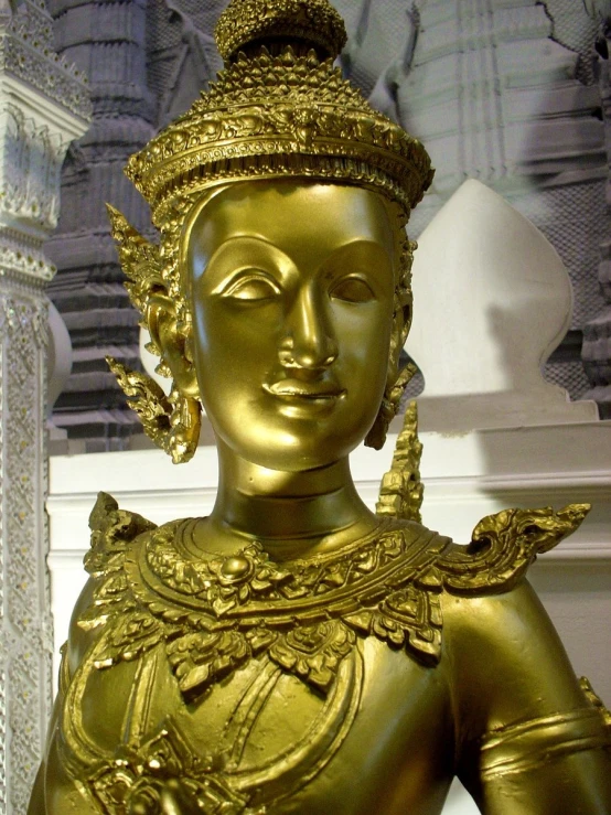 a golden statue in front of a white sculpture