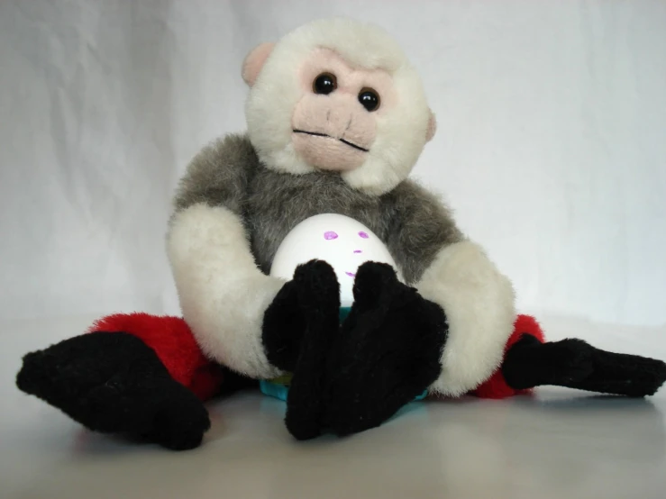 there is a stuffed monkey holding an egg