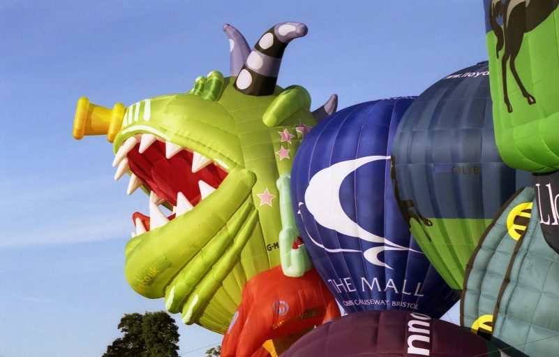 many inflated kites that look like dinosaurs and dragon heads