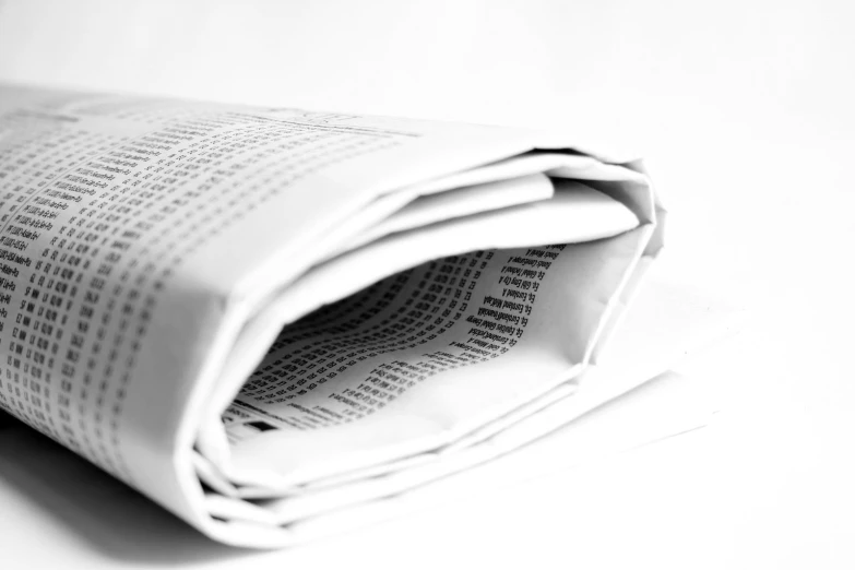 two folded up newspapers sit on a white table
