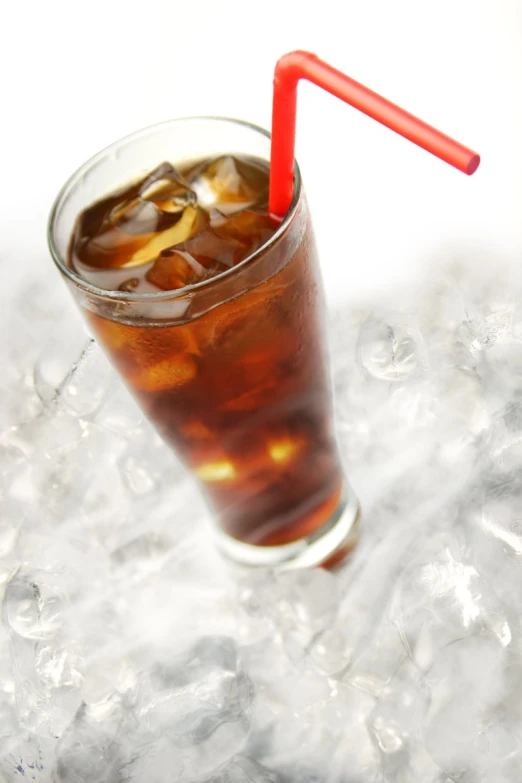 a glass with ice and soda sitting on a table