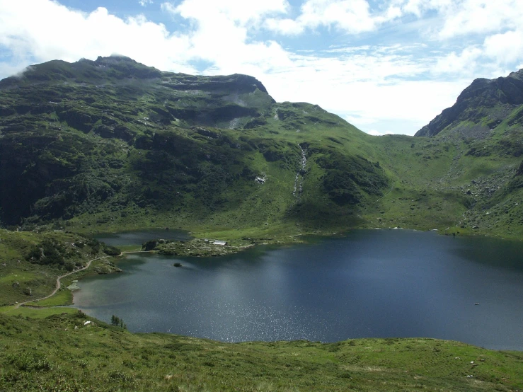 a blue lake in the middle of some green hills