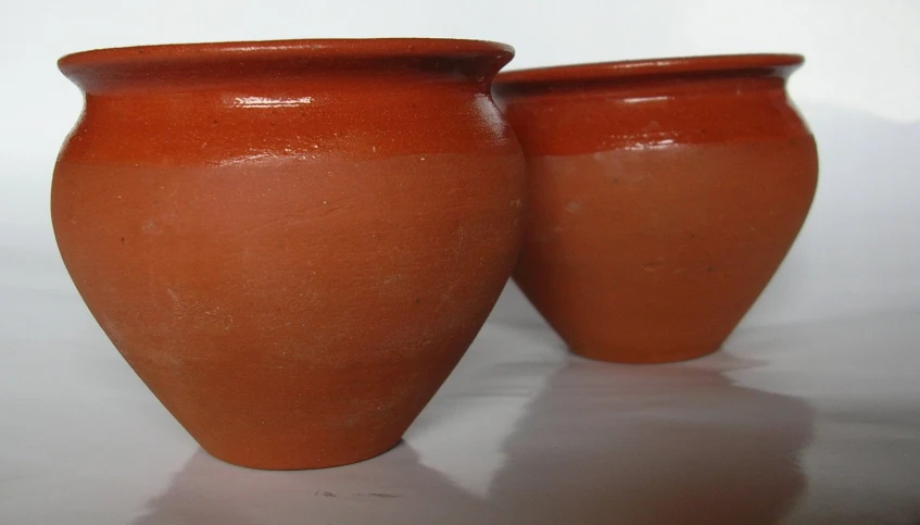 two brown ceramic vases sitting on a table