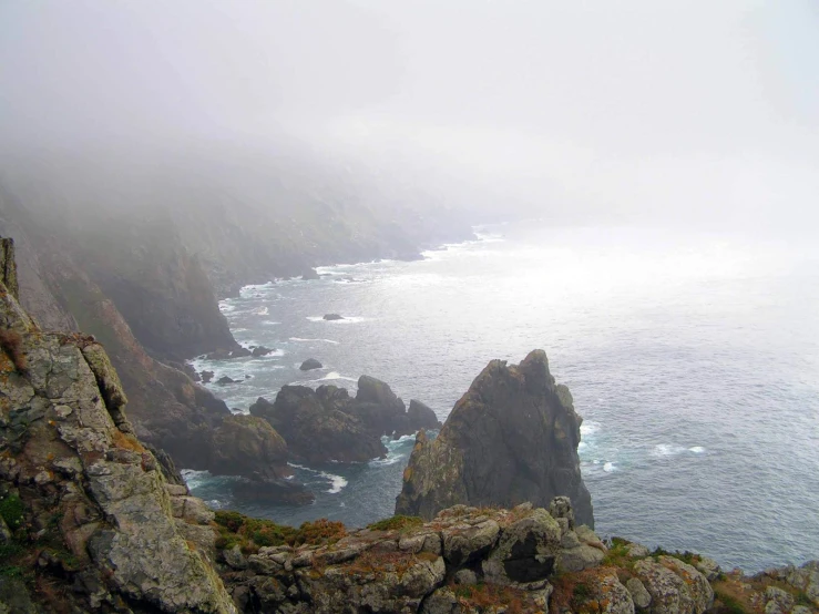 the ocean and a rock outcropping on a foggy day