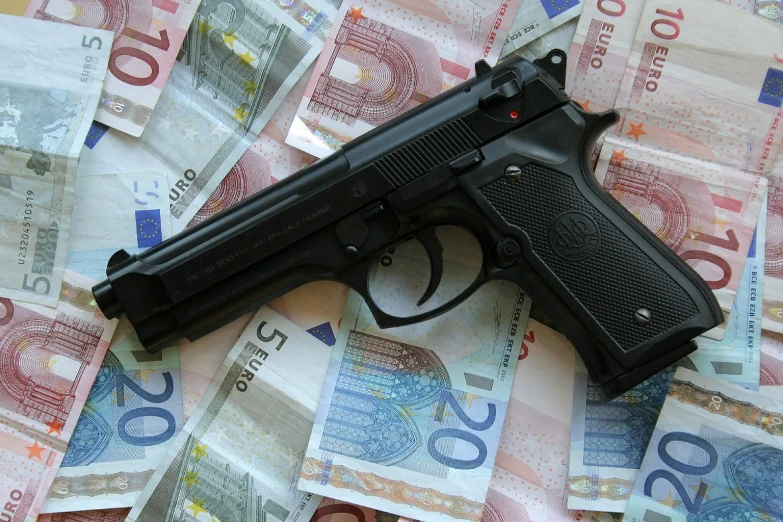 a gun is lying on bank notes